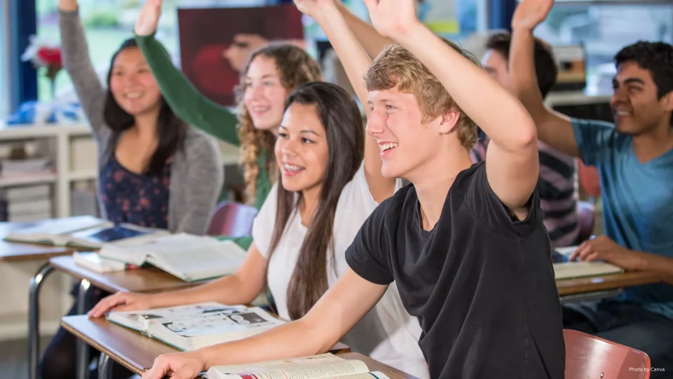 Students in Classroom raising Hands